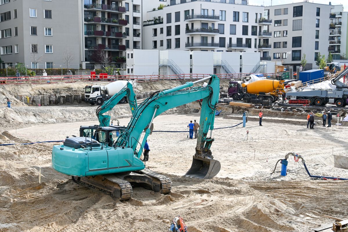 Pelleteuse creusant les fondations avec camions toupie béton sur le chantier – Blue Vert